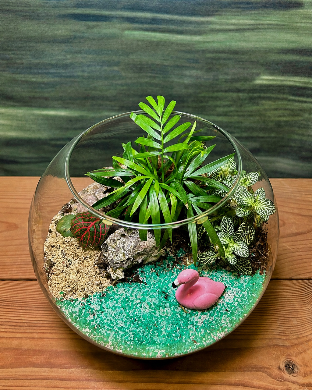 Palm Oasis Terrarium from Planterie with a dwarf palm and vibrant fittonia plants alongside blue sand ocean and an elegant swan miniature, creating a captivating lakeside scene for desk and bedside table as plant gifts in Delhi for housewarmings